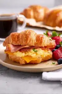 Croissant breakfast sandwich with eggs bacon ham and melted cheese