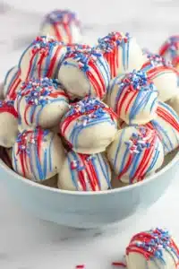 Patriotic Oreo Balls with white chocolate, red and blue drizzle, and festive sprinkles
