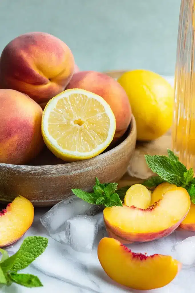 Fresh Peach Lemonade ingredients with peaches, lemons, mint, and ice
