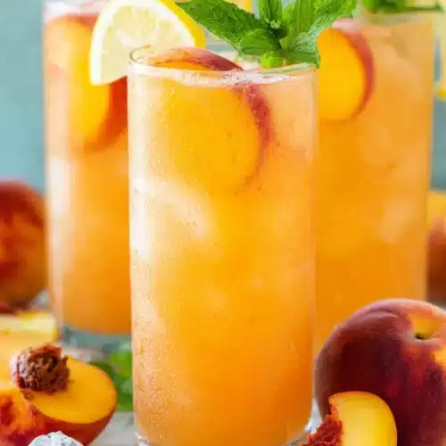 Fresh peach lemonade with lemon slices, mint, and ice in tall glasses