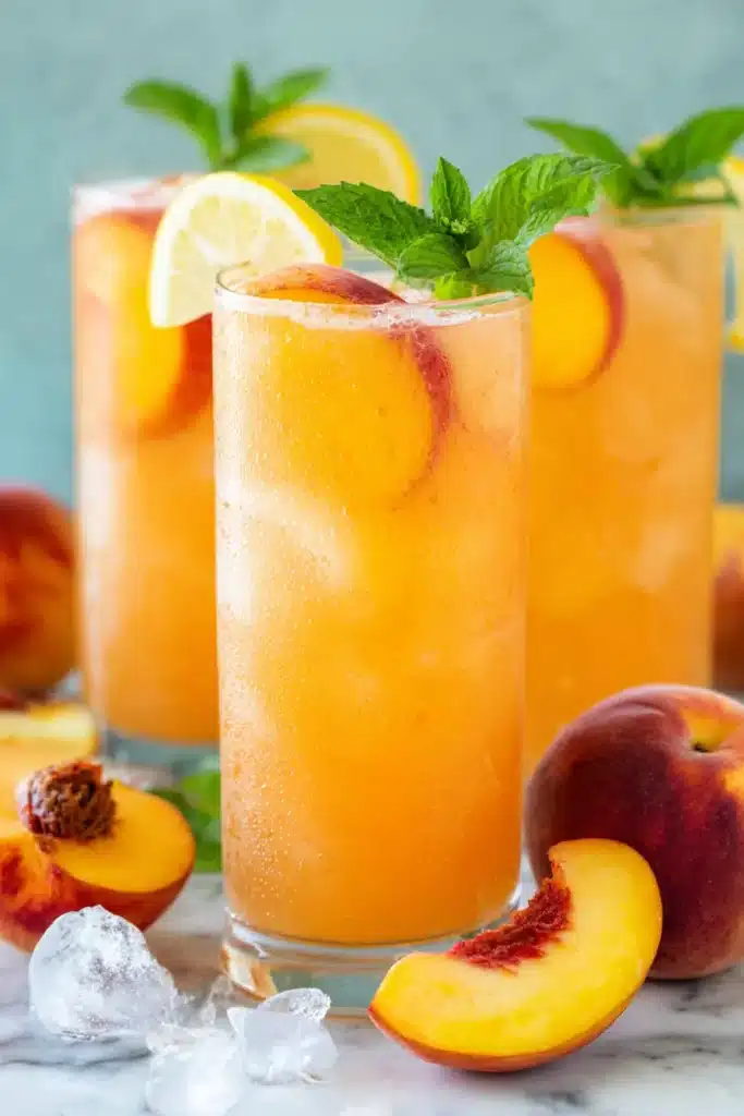 Fresh peach lemonade with lemon slices, mint, and ice in tall glasses