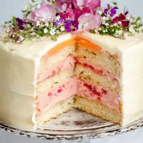 Rose Rhubarb Layer Cake slice with pink cream filling and floral decoration