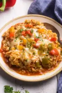 Stuffed pepper casserole with melted cheese, rice, sausage, and bell peppers