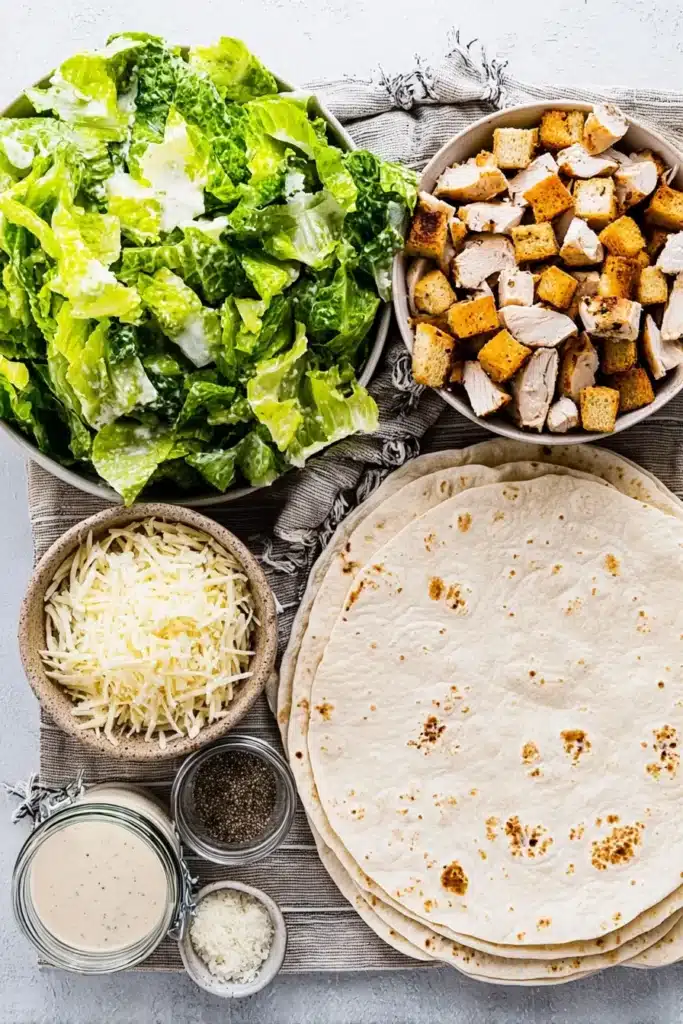 Chicken Caesar Wrap: Easy, Creamy, and Perfect for Busy Nights 2 Chicken Caesar Wrap ingredients with romaine, chicken, tortillas, Parmesan, and croutons