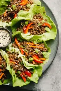 Ground Beef Lettuce Wraps with sesame seeds, peppers, and carrots in crisp butter lettuce