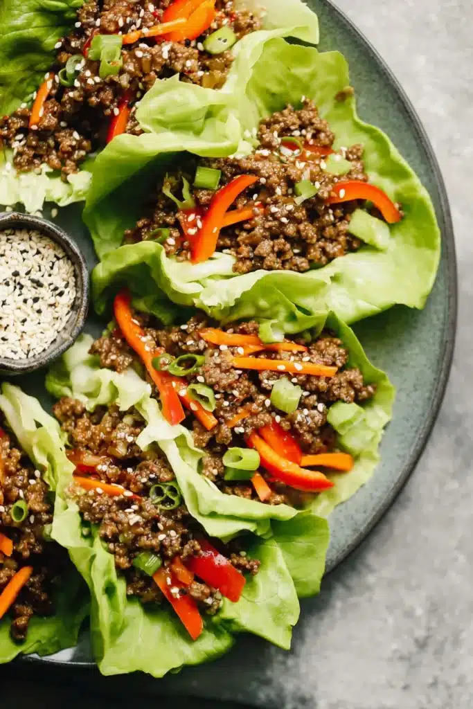 Ground Beef Lettuce Wraps with sesame seeds, peppers, and carrots in crisp butter lettuce