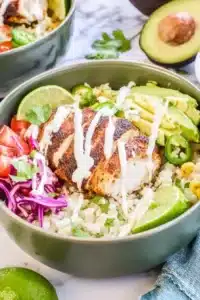 Low Carb Fish Taco Bowls with cod, cauliflower rice, avocado, slaw, and lime crema